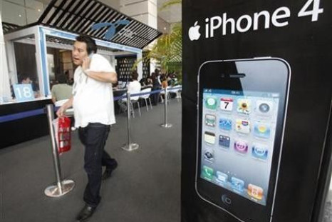 A man walks past an advertisement for an iPhone 4 displayed at a shop in Bangkok