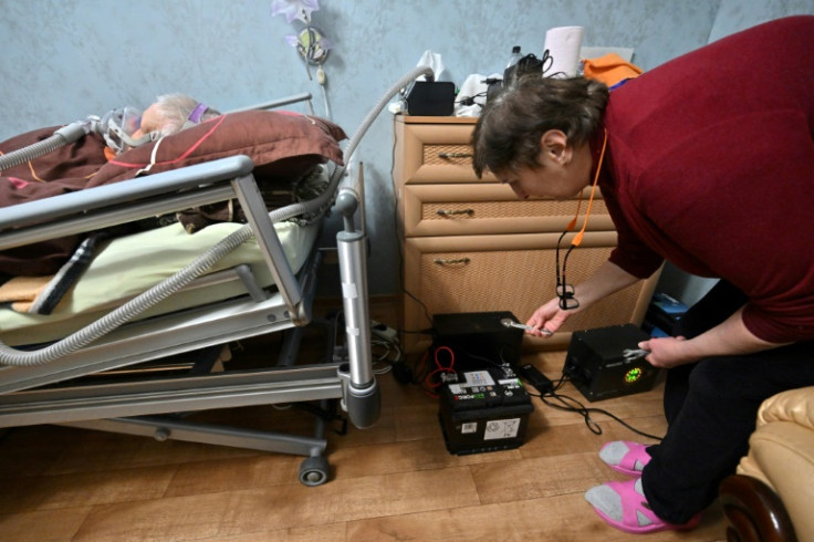 Lyudmyla Mozgova checks a power storage and extra batteries she has set up to keep the ventilator running