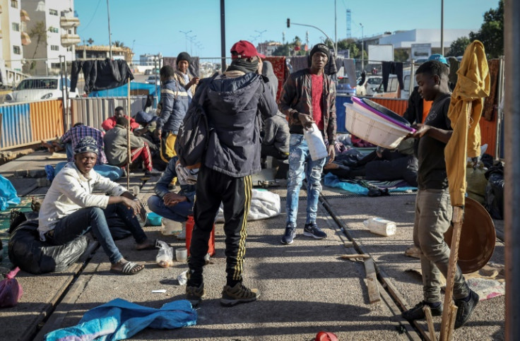 Opposite the Oulad Ziane bus station, some migrants cook in a makeshift kitchen while others lie exhausted on the pavement