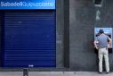 A man uses an ATM at a branch of Sabadell bank in the Basque town of Guernica