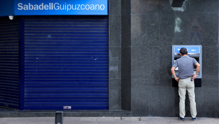 A man uses an ATM at a branch of Sabadell bank in the Basque town of Guernica