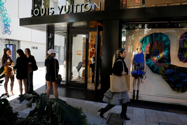 People walk past the Louis Vuitton store at Miami Design District, in Miami