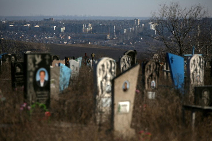 Graves line a hill overlooking the Ukrainian town of Bakhmut behind a cemetery in Donetsk region