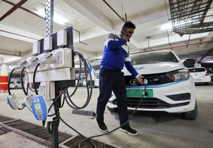 A man charges an electric vehicle (EV) at the charging hub of Indian ride-hailing BluSmart Electric Mobility in Gurugram