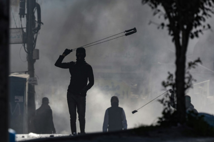Demonstrators hurl rocks at Israeli troops in the West Bank town of Al-Ram as Palestinians vent their anger over Thursday's deadly raid in Jenin