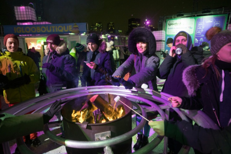 Festival-goers warm up and grill marshmallows next to a fire at Montreal's Igloofest on January 26, 2023