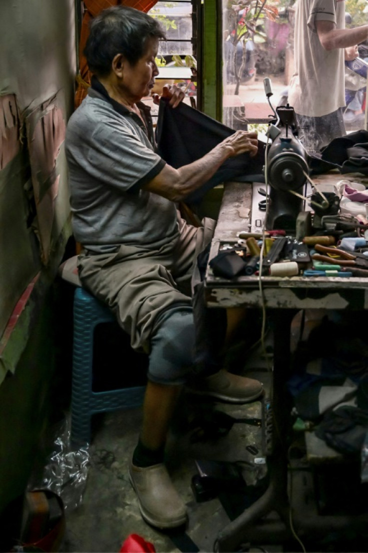 Former leprosy patient Cun San, who is also a tailor, works inside a shop as he wears a prosthetic leg made by Saga