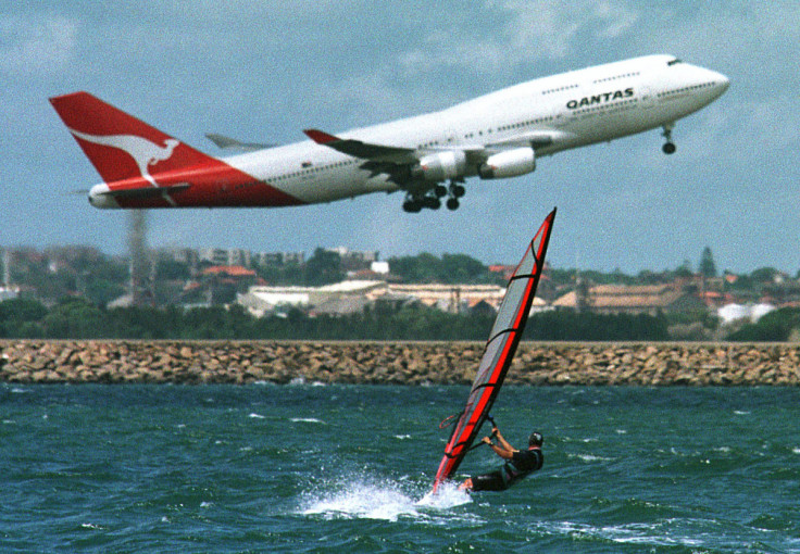 A windsurfer on Sydney's Botany Bay heads towards the Sydney Airport runway as a Qantas Boeing 747 p..