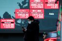 A passerby walks past an electric screen displaying various Asian countries' stock price indexes outside a brokerage in Tokyo