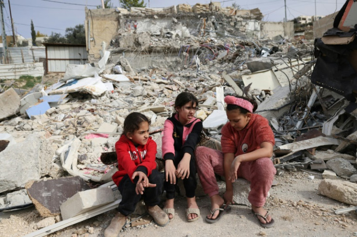Palestinian girls sit in the debris of the house of Rateb Hatab Shukairat, after it was demolished by Israeli bulldozers, in the east Jerusalem neighbourhood of Jabal Mukaber on January 29, 2023