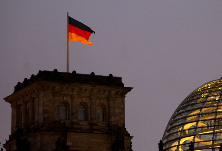 A German national flag flies atop the illuminated Reichstag building in Berlin
