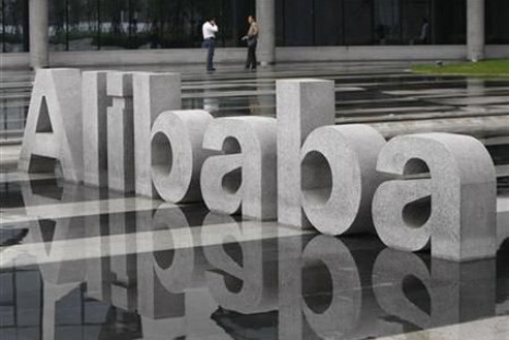 Two men chat beside a logo of Alibaba (China) Technology Co. Ltd at its headquarters on the outskirts of Hangzhou