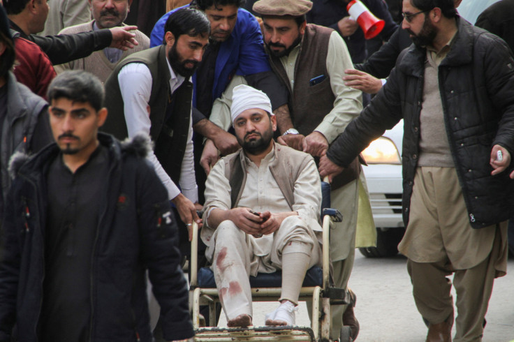 Men move an injured victim on a wheel chair, after a suicide blast in a mosque, at hospital premises in Peshawar