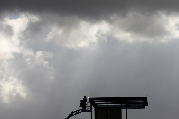 A construction worker welds under stormy clouds high atop a structure being built by the U.S. Government next to the Mexican border in San Diego