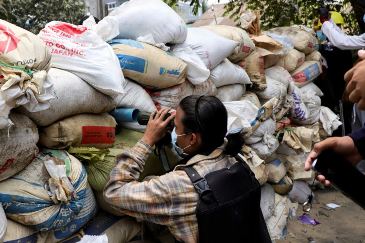 Anti-coup protester looks out through a barricade during a protest against the military rule, in Yangon