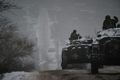 Ukrainian servicemen ride infantry combat vehicles driving down an icy road in the Donetsk region