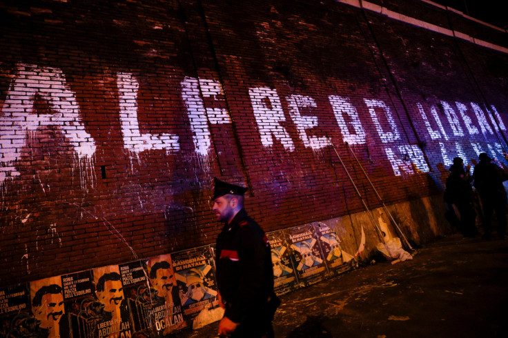 A Carabinieri police officer walks past a writing on a wall asking for freedom for Italian anarchist Alfredo Cospito