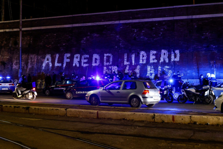 Police and Carabinieri work near a writing on a wall asking for freedom for Italian anarchist Alfredo Cospito