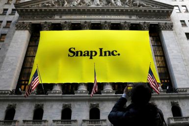 A woman photographs a banner for Snap Inc. on the facade of the New York Stock Exchange