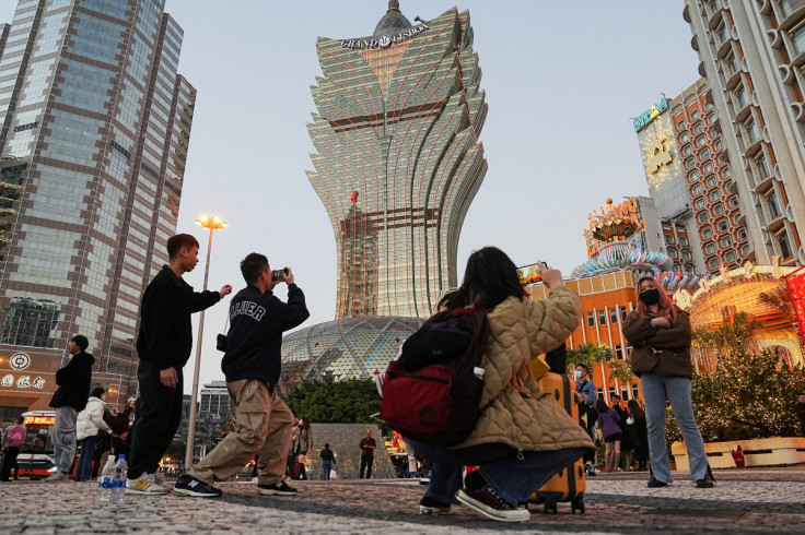 Visitors pose for photos outside the Grand Lisboa casino operated by SJM Holdings during Lunar New Year in Macau