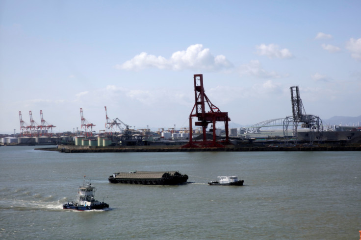 A boat tows a barge of coal across the port of Osaka