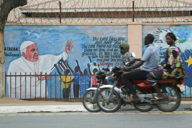 People ride past a mural depicting Pope Francis ahead of his visit in Juba