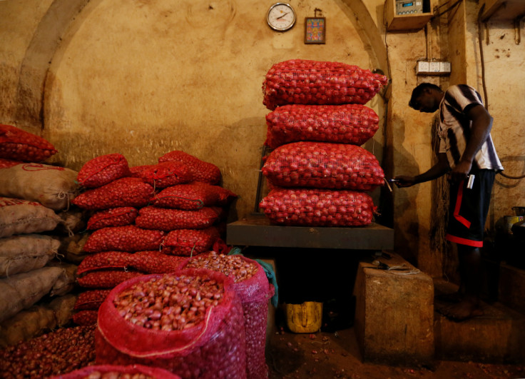 A man weighs sacks of red onions at a shop near a main market in Colombo