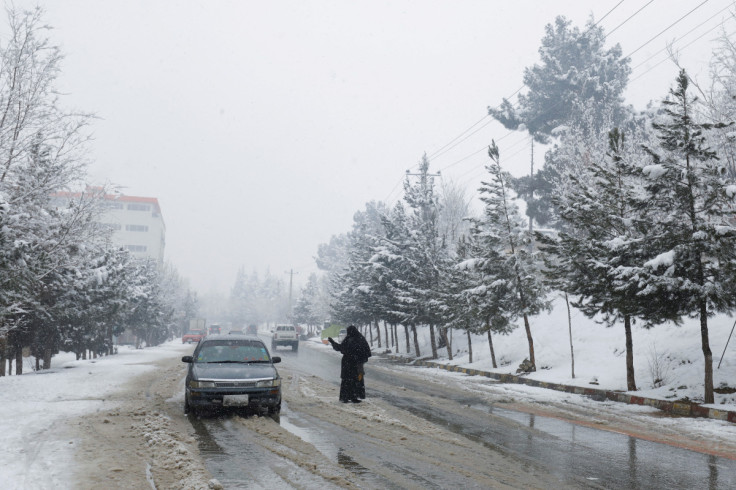 An Afghan woman begs on a snowy day in Kabul