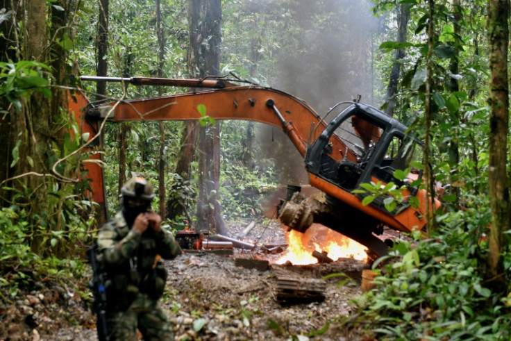 A Colombian soldier stands guard as heavy machinery used at an illegal gold mine is destroyed