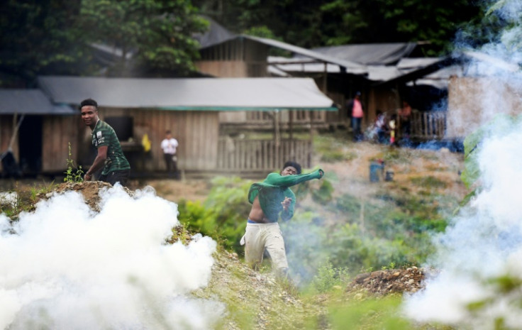 Colombian villagers throw stones at riot police who respond with tear gas during a raid on an illegal gold mine in Triangulo de Telembi