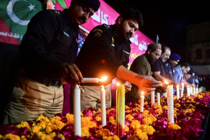 Police officers and residents of Karachi pay tribute to the victims of Monday's suicide bombing at a mosque in Peshawar