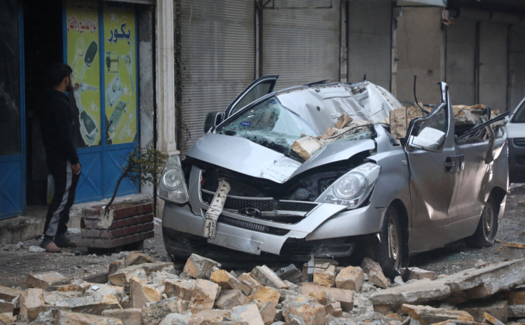 A man stands near a damaged vehicle, following an earthquake, in rebel-held Azaz