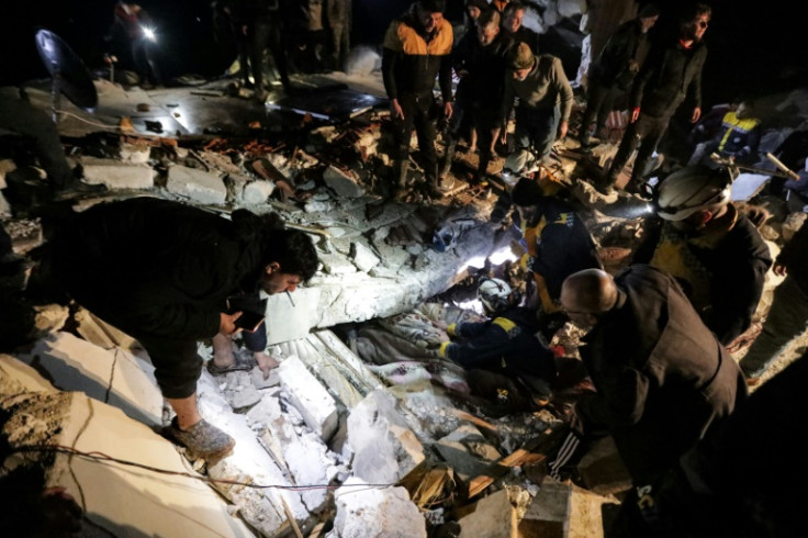 People look on as Syrian rescuers retrieve an injured man from the rubble of a collapsed building following a 7.8-magnitude earthquake that had its epicentre in southeastern Turkey