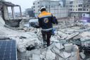 A rescue worker carries a child at the site of a damaged building, following an earthquake, in rebel-held Azaz