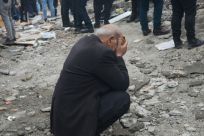 A man puts his head in his hands as people search for survivors in Diyarbakir, southeast Turkey