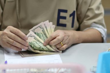A bank employee counts U.S. dollar notes at a Kasikornbank in Bangkok