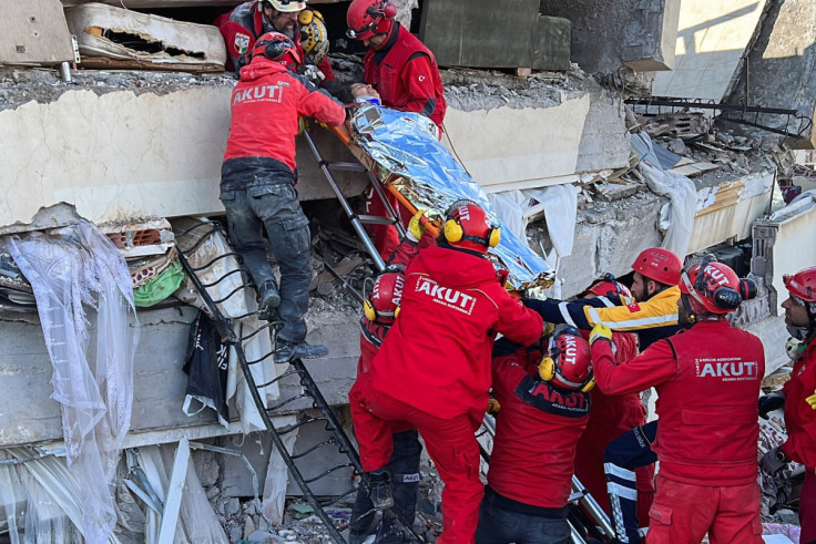 Rescuers carry a woman after she was evacuated from under a collapsed building following an earthquake in Kahramanmaras