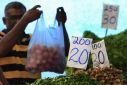 Price lists are seen at vegetable stall as a vendor prepares a bag for a customer at a main market in Colombo