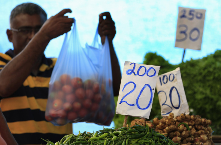 Price lists are seen at vegetable stall as a vendor prepares a bag for a customer at a main market in Colombo