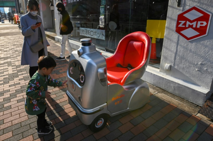 A child and his mother look at a mobility robot RakuRo, developed by Tokyo-based robotics firm ZMP, at the company's service station in Tokyo