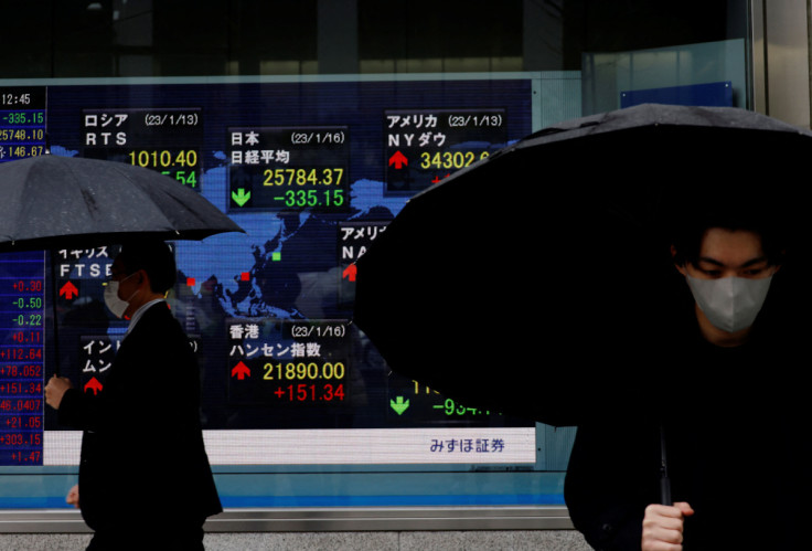 Men walk past an electric board displaying Nikkei and other countries’ indexes outside a brokerage in Tokyo