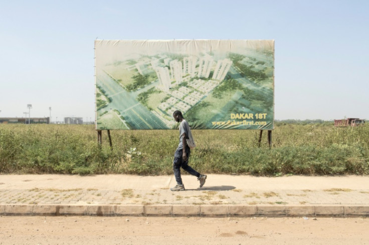 Future promise: A construction worker walks past an advertising hoarding for the new city being built in Diamniadio