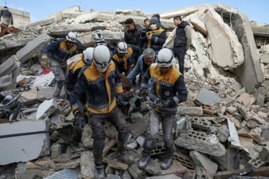 White Helmets rescuers emerge from the rubble with a casualty from the earthquake in the village of Azmarin, in Syria's rebel-held northwestern Idlib province