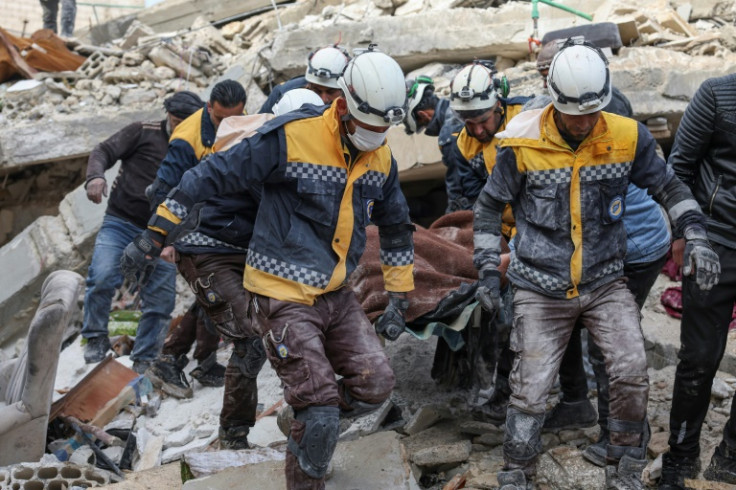 Members of the Syrian Civil Defense, or White Helmets, carry a quake victim from the rubble