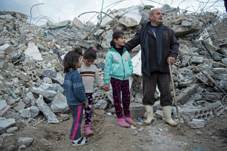 A family stands amid the rubble of a collapsed building in Jableh