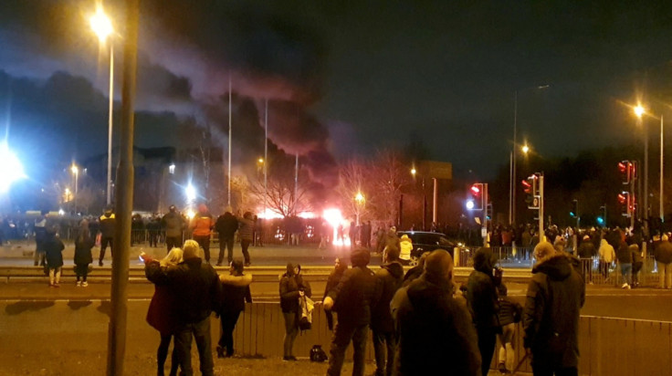People watch a fire outside a hotel offering refuge to asylum seekers after a protest in Knowsley