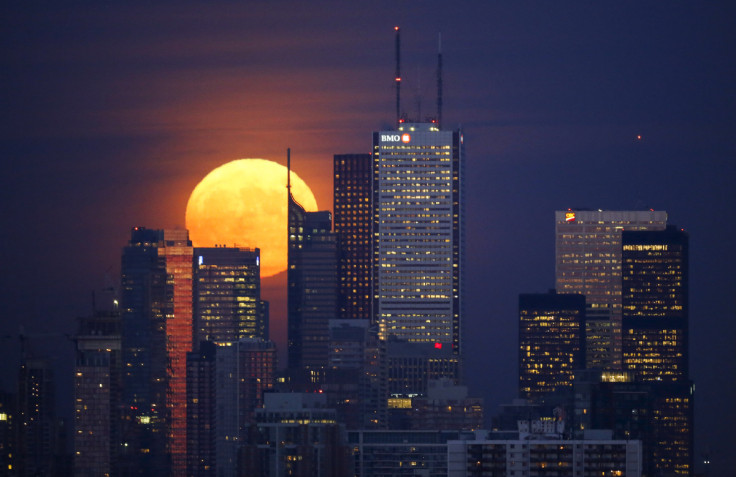 The moon rises behind the skyline and financial district of Toronto