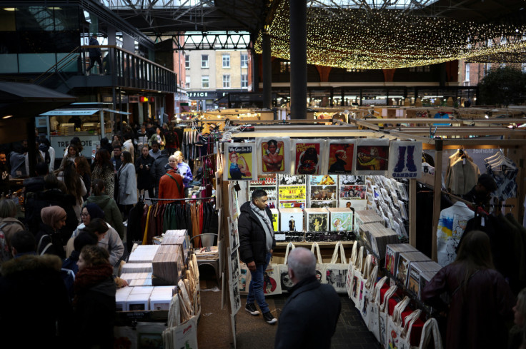 A market trader stands at his stall as people walk past in Old Spitalfields Market in London
