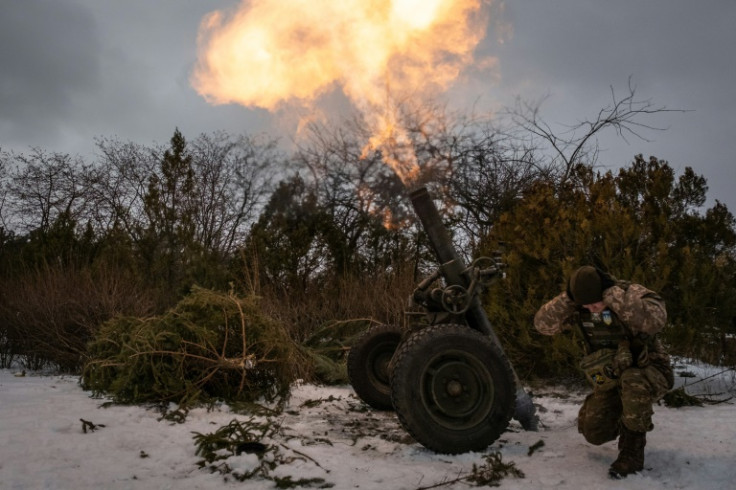 A Ukrainian serviceman  covers his ears while firing a mortar
