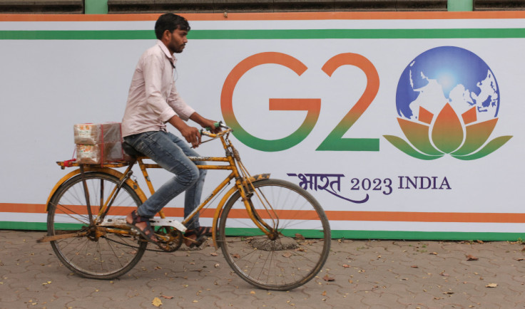 A man rides a bicycle past the hoarding of India's G20 presidency, on a street in Mumbai